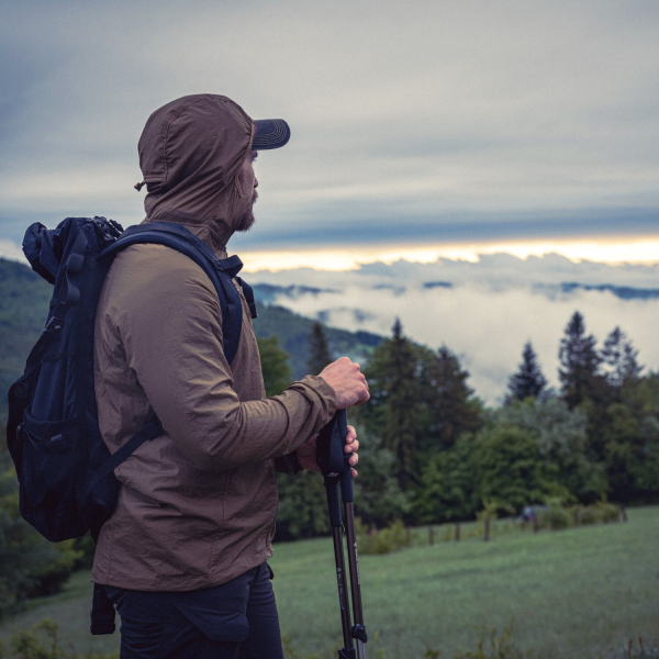 Ein Mann beim Wandern der die Helikon Tex Jacke und einen Rucksack trägt.